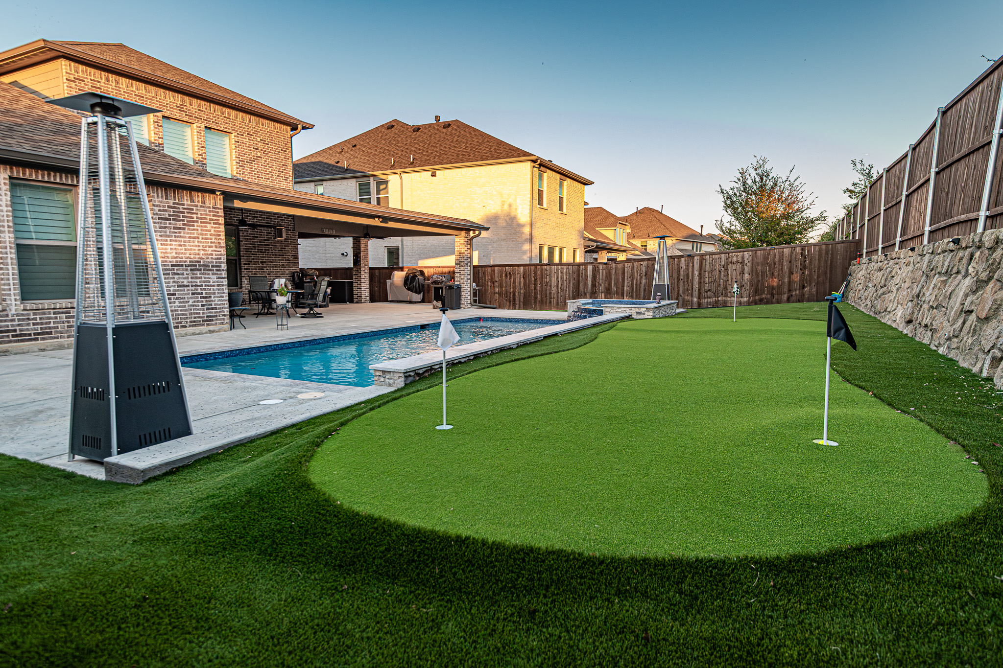 Photo of a Putting Green with a new pool in the background, houses in the far background